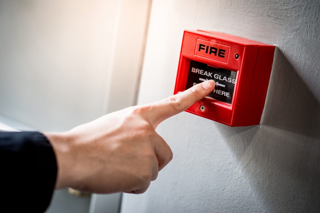 Male pointing to fire safety alarm in office workplace